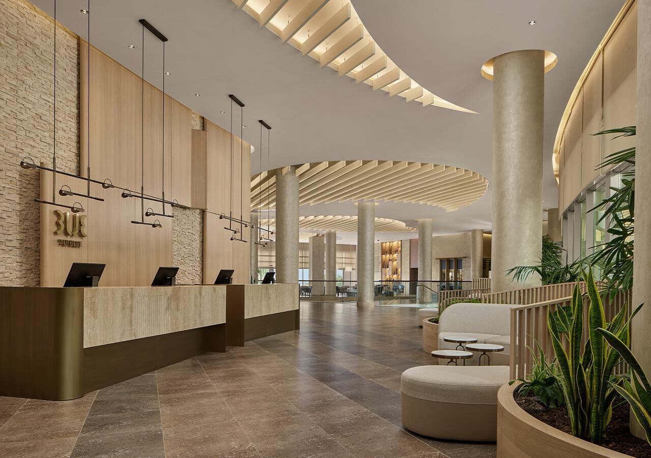 A spacious lobby with a reception desk, seating area, and a curved ceiling design.