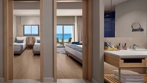 Una camera d'albergo con un letto, una scrivania, una sedia, un bagno con lavandino e specchio, e vista mare.