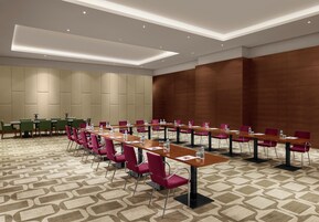 A conference room with multiple tables and chairs, equipped with water bottles and nameplates.