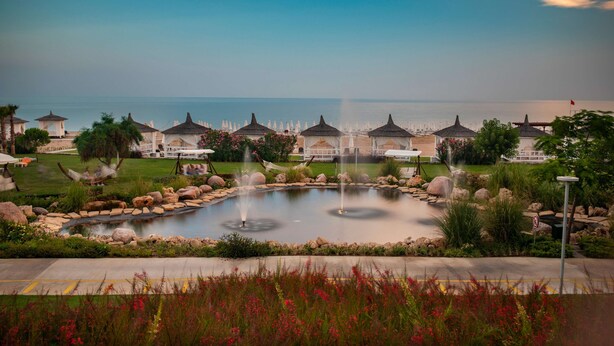 Un resort con uno stagno centrale, lettini e ombrelloni.