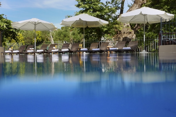 Una piscina al aire libre, sombrillas, sillones reclinables de piscina