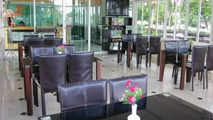 A modern restaurant with glass partitions, leather chairs, and a central dining table with a vase of flowers. - Fahproundfon Hotel (Nakhon Ratchasima)