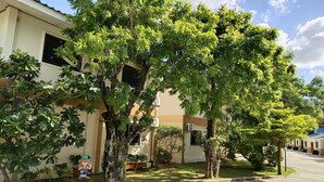 A building with multiple windows, surrounded by lush green trees and a well-maintained lawn. - Fahproundfon Hotel (Nakhon Ratchasima)