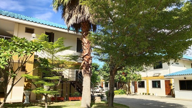 A residential area with a curved road, houses with blue roofs, and a palm tree. - Fahproundfon Hotel (Nakhon Ratchasima)