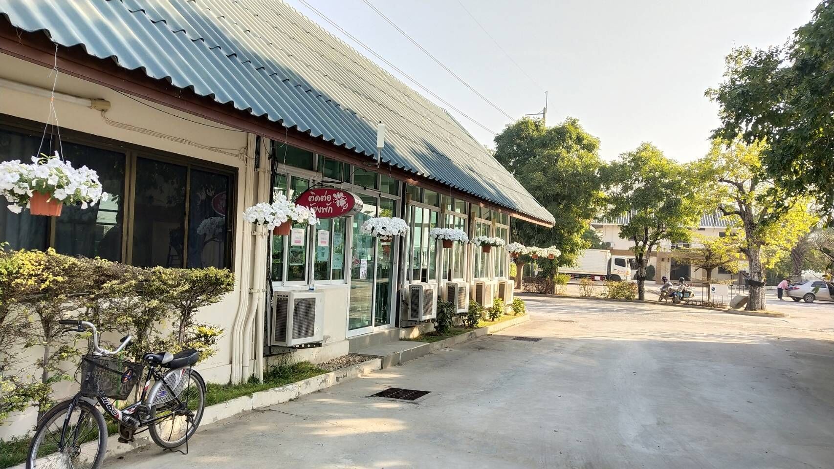 A building with a corrugated metal roof, air conditioning units, and a bicycle parked outside.