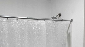 A bathroom with a shower curtain, a toilet, and a wooden floor. - Economy Inn Victorville (Victorville)