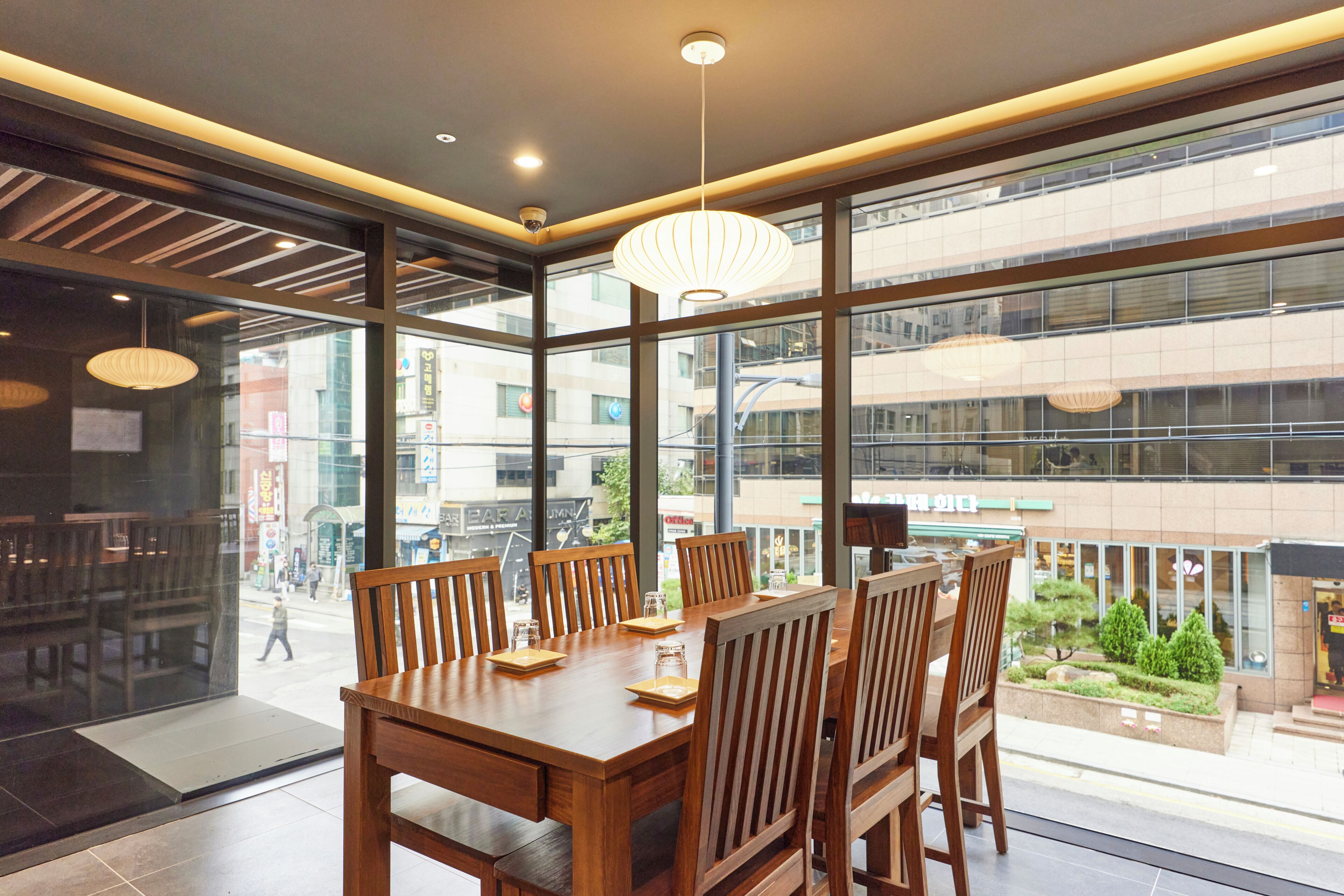A modern dining area with a large table and chairs, large windows offering a view of the cityscape.