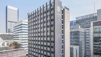 A modern hotel building with a prominent 'URI & HOTEL' sign, featuring a grid-like facade and multiple floors.