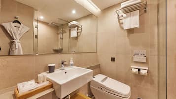 Un baño moderno con lavamanos, inodoro y ducha. Hay toallas y artículos de aseo en la encimera.