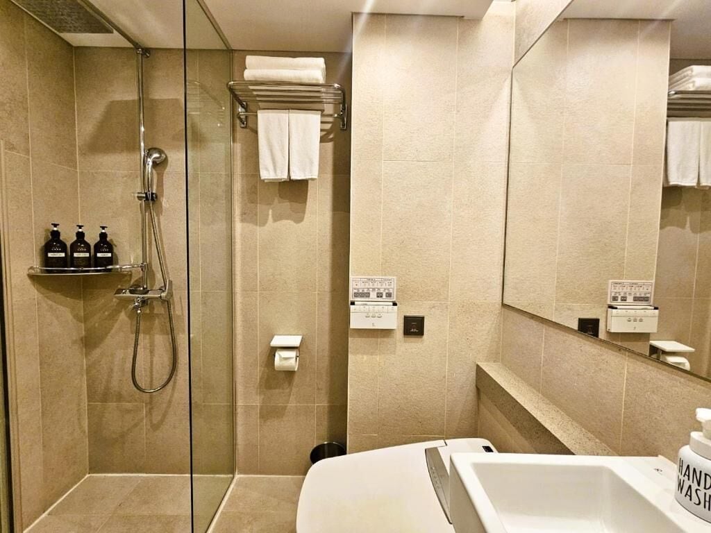 Un baño moderno con ducha de vidrio, lavamanos blanco y espejo.
