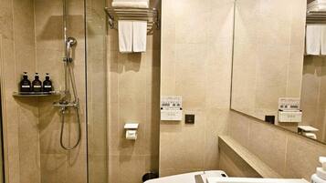 Un baño moderno con ducha de vidrio, lavamanos blanco y espejo.