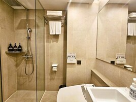 Un baño moderno con ducha de vidrio, lavamanos blanco y espejo.