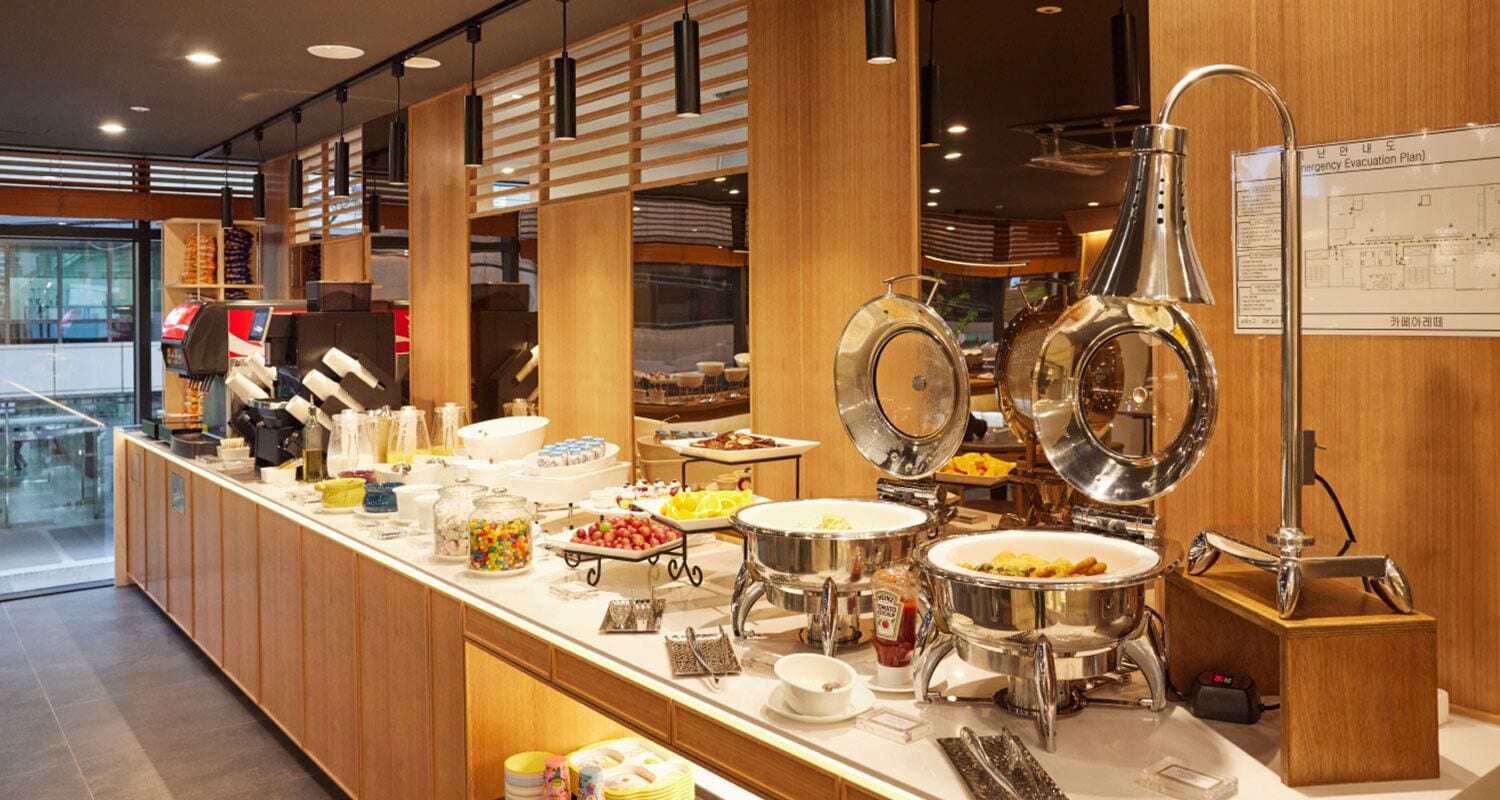 A buffet setup with various food items and serving utensils.