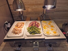 Un bufé con pescado a la parrilla, judías verdes y huevos fritos.