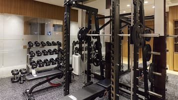 A gym with weightlifting equipment, benches, and dumbbells.