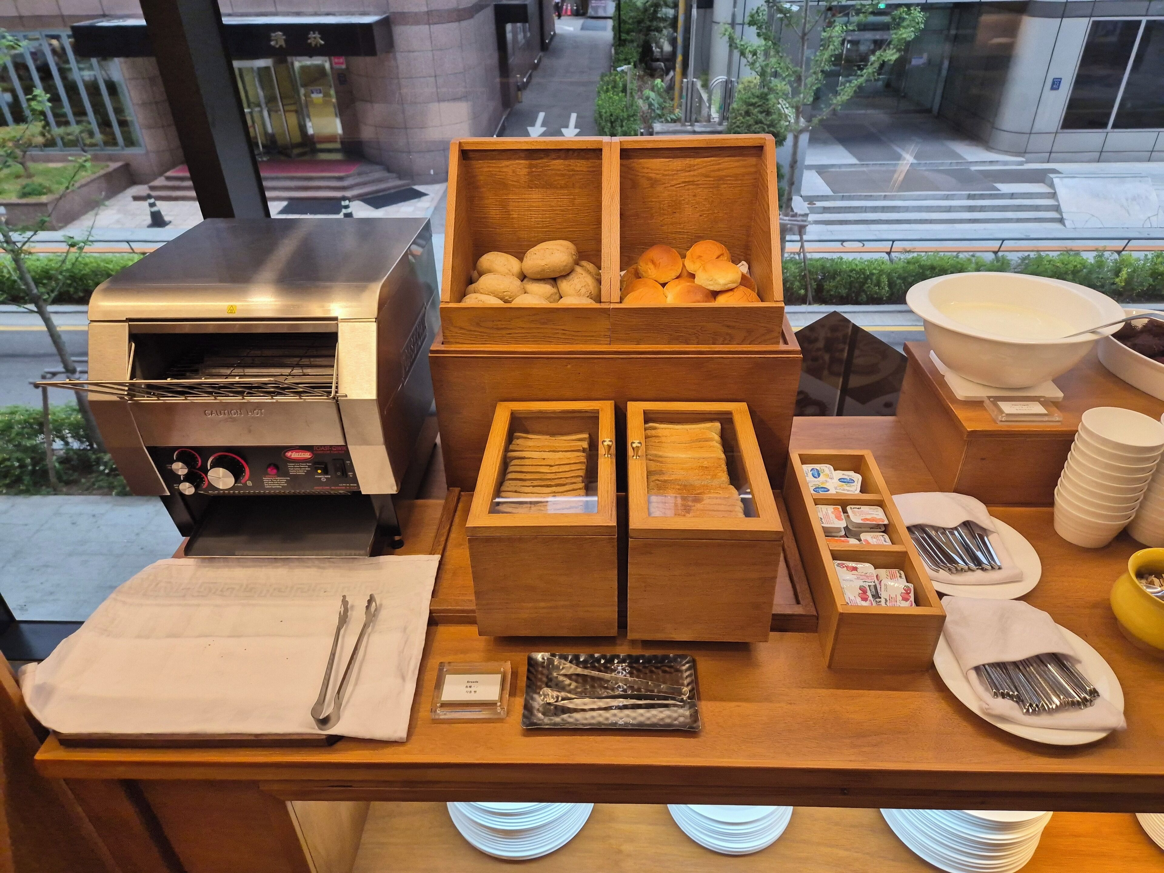 A buffet setup with a grill, bread, and condiments.