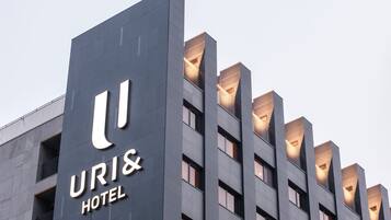 A modern hotel building with a prominent sign reading "URI& HOTEL".