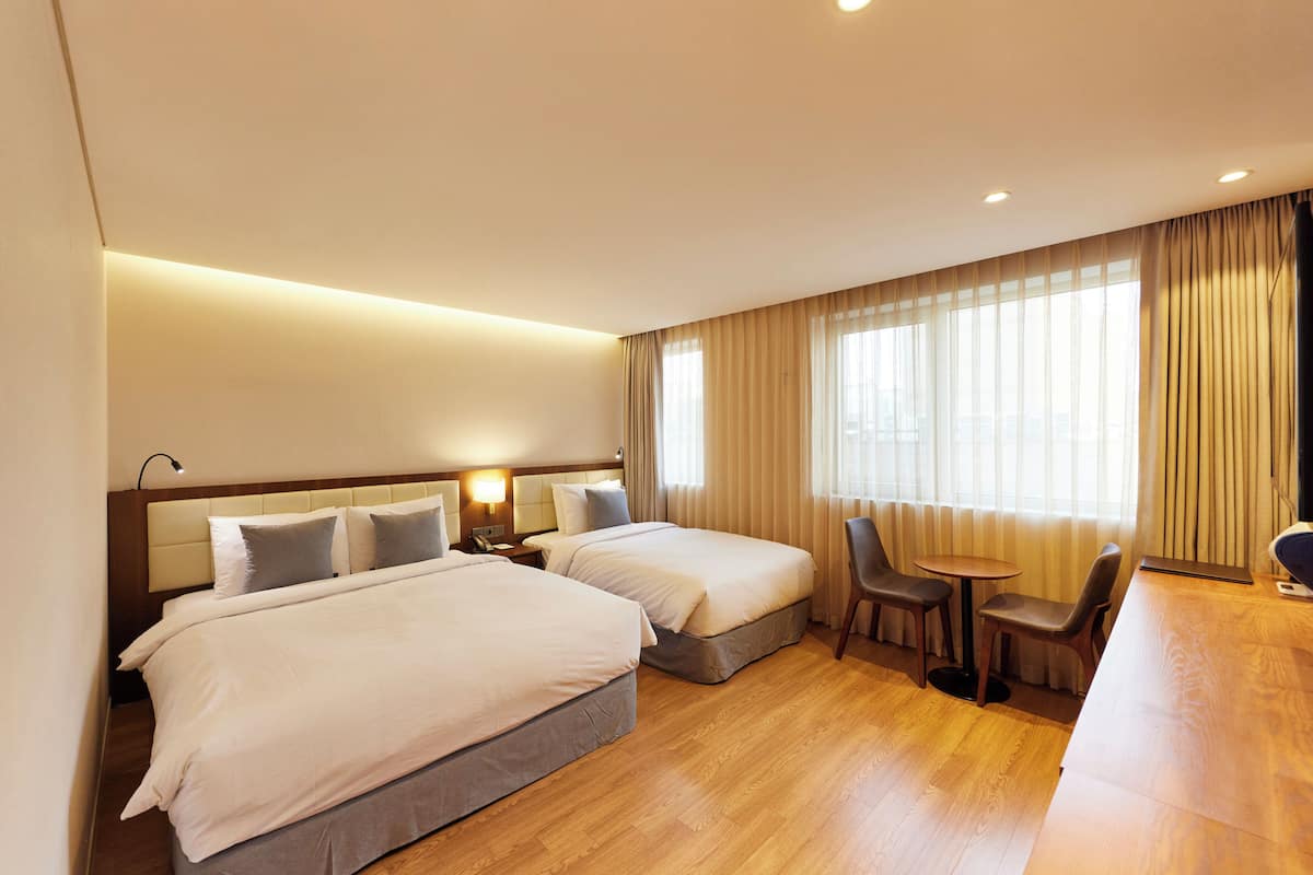 Una habitación de hotel con dos camas, una mesita, sillas y un escritorio.