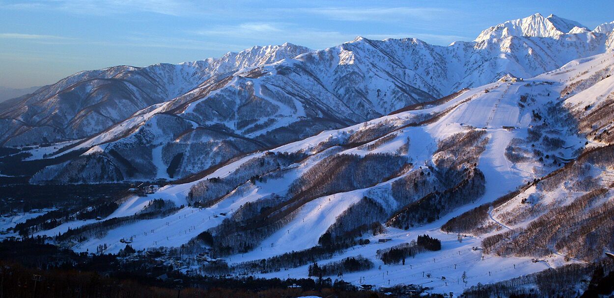 A snow-covered mountain landscape with ski slopes and a clear sky.