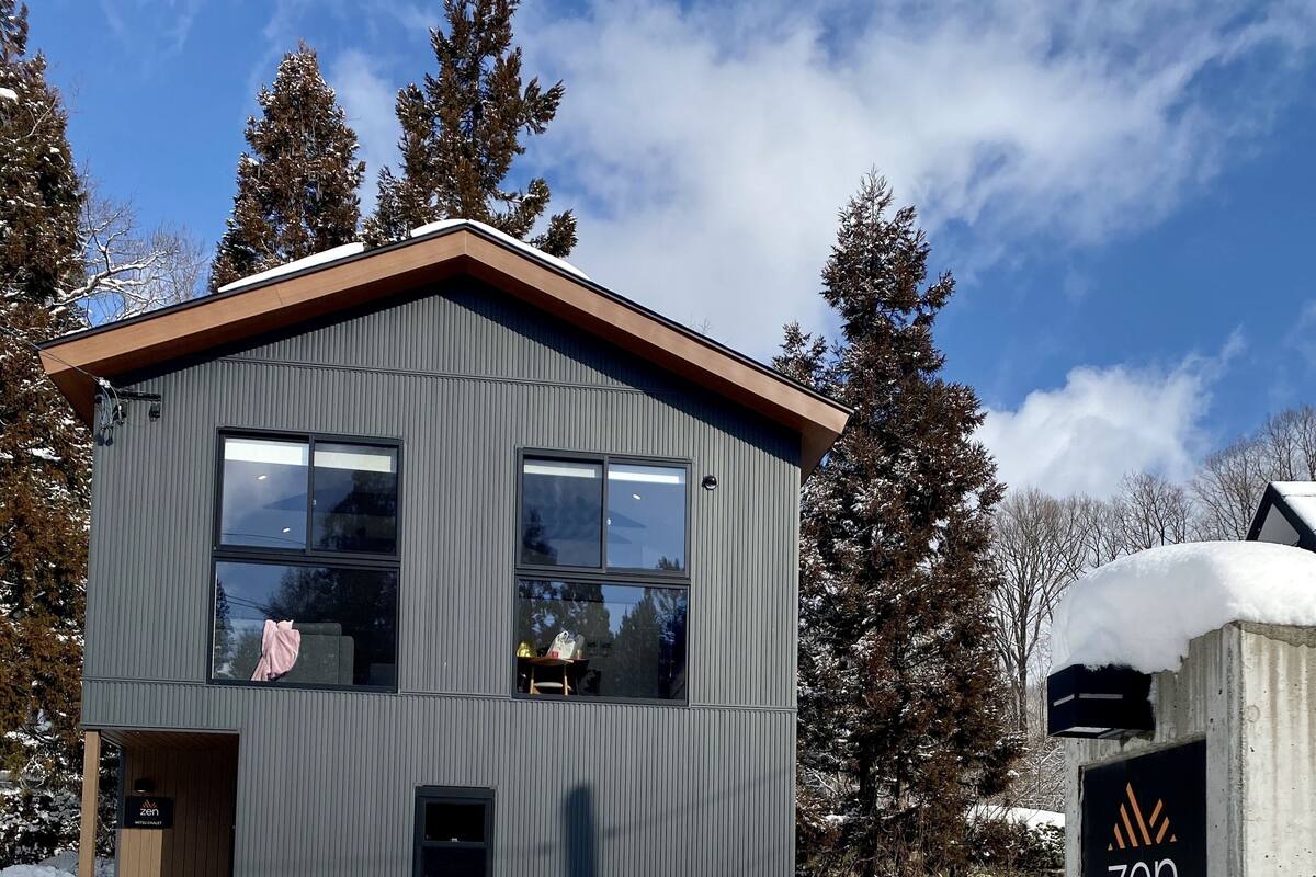 A modern building with a wooden door, a small porch, and a sign reading "zen chalets".