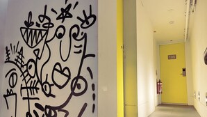 A hallway with a yellow door marked '105', a fire extinguisher, and a wall with abstract graffiti. - Sydney Boutique Hotel (Darlinghurst)