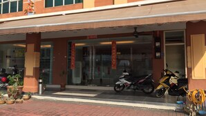 A hotel entrance with a covered entrance, a glass door, and a motorcycle parked outside.