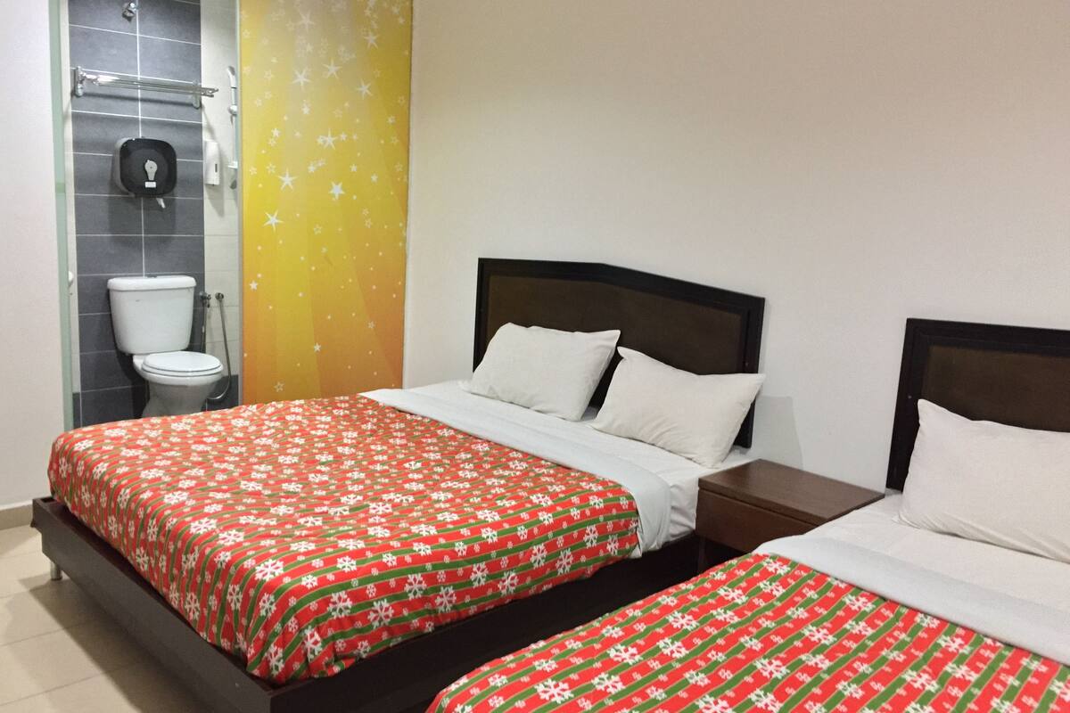 A hotel room with two beds, a bathroom, and a yellow wall with star patterns.