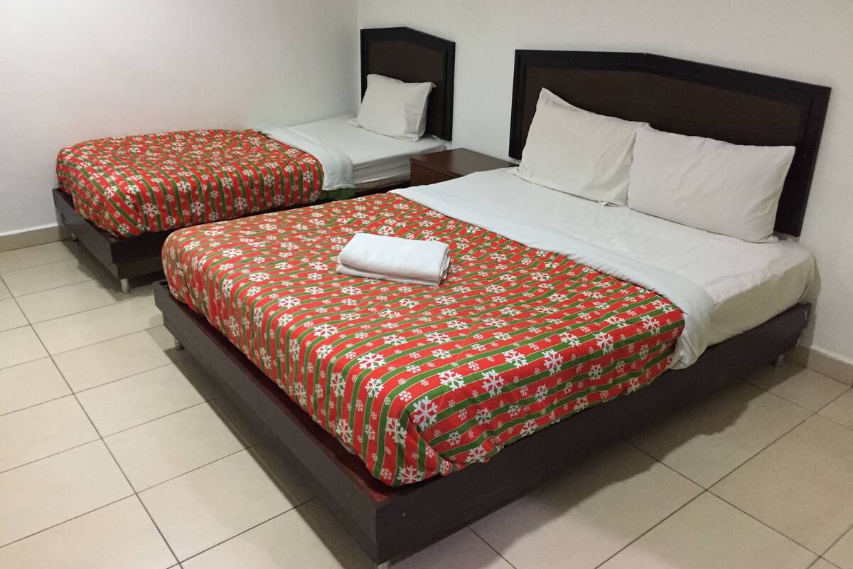 A hotel room with two single beds and a larger bed.