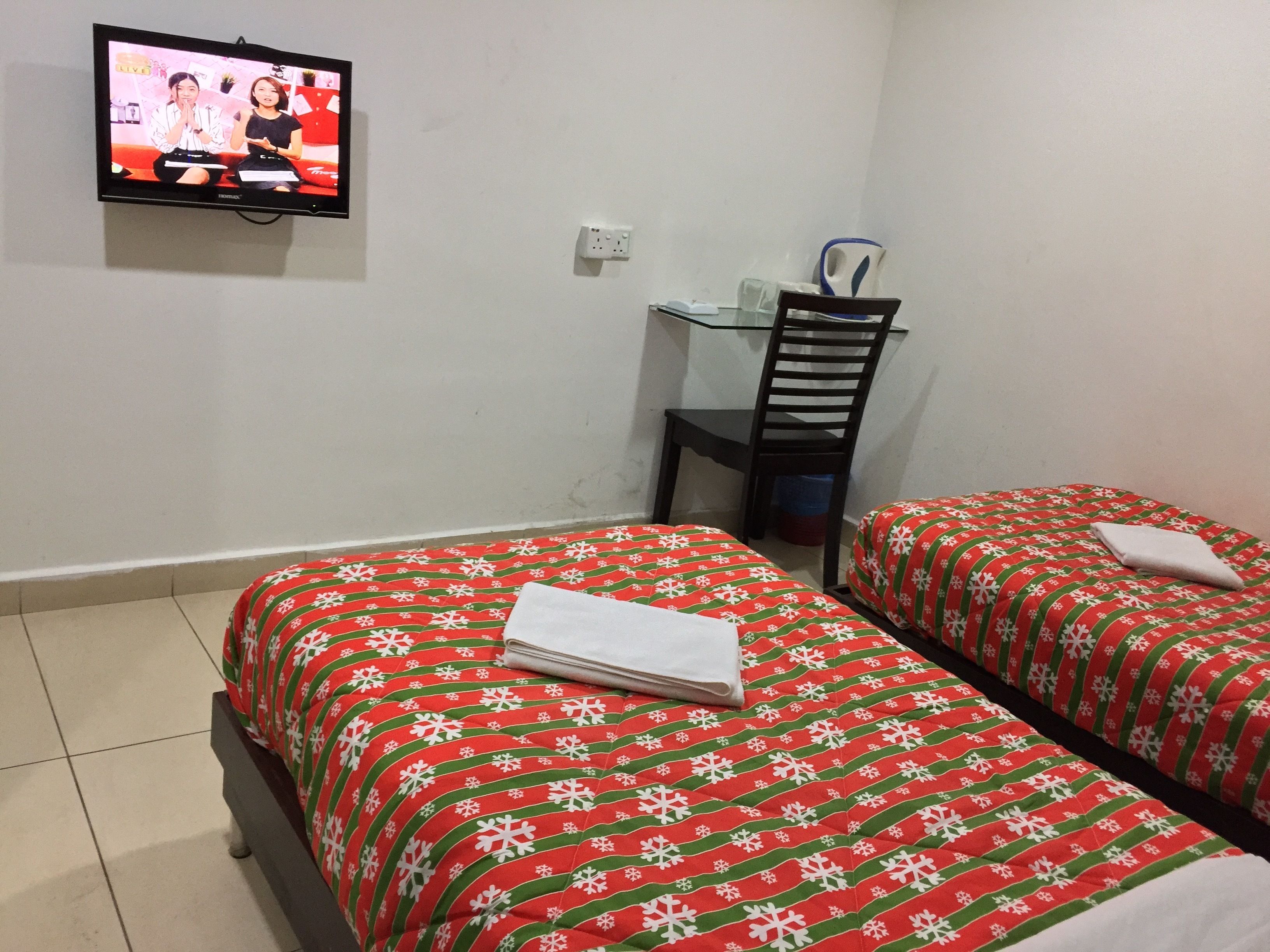 Una habitación de hotel con dos camas, un televisor en la pared, un escritorio y una silla.