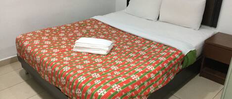 A neatly made bed with a red and white patterned bedspread and white pillows.