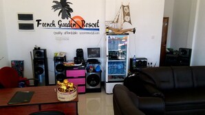 Una sala de estar con sofá, una mesa de comedor, un refrigerador lleno de bebidas y un equipo de sonido.