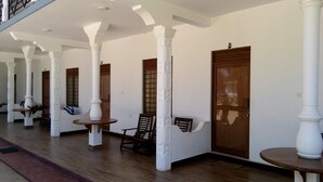 Un espacio al aire libre techado con columnas blancas, puertas de madera y mesas.