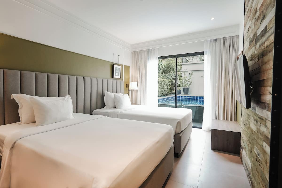 Habitación de hotel con dos camas, un ventanal grande y vista a una piscina.