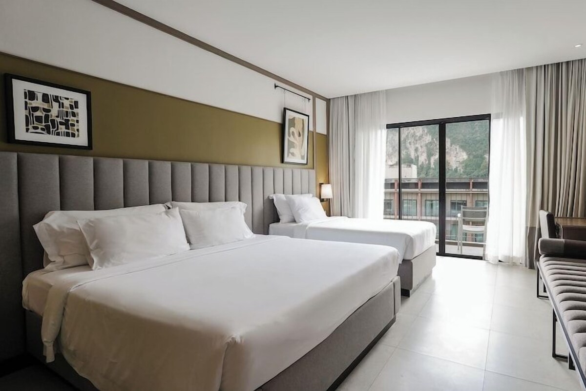 Une chambre d’hôtel avec deux lits, un canapé, une télévision et un balcon avec vue.