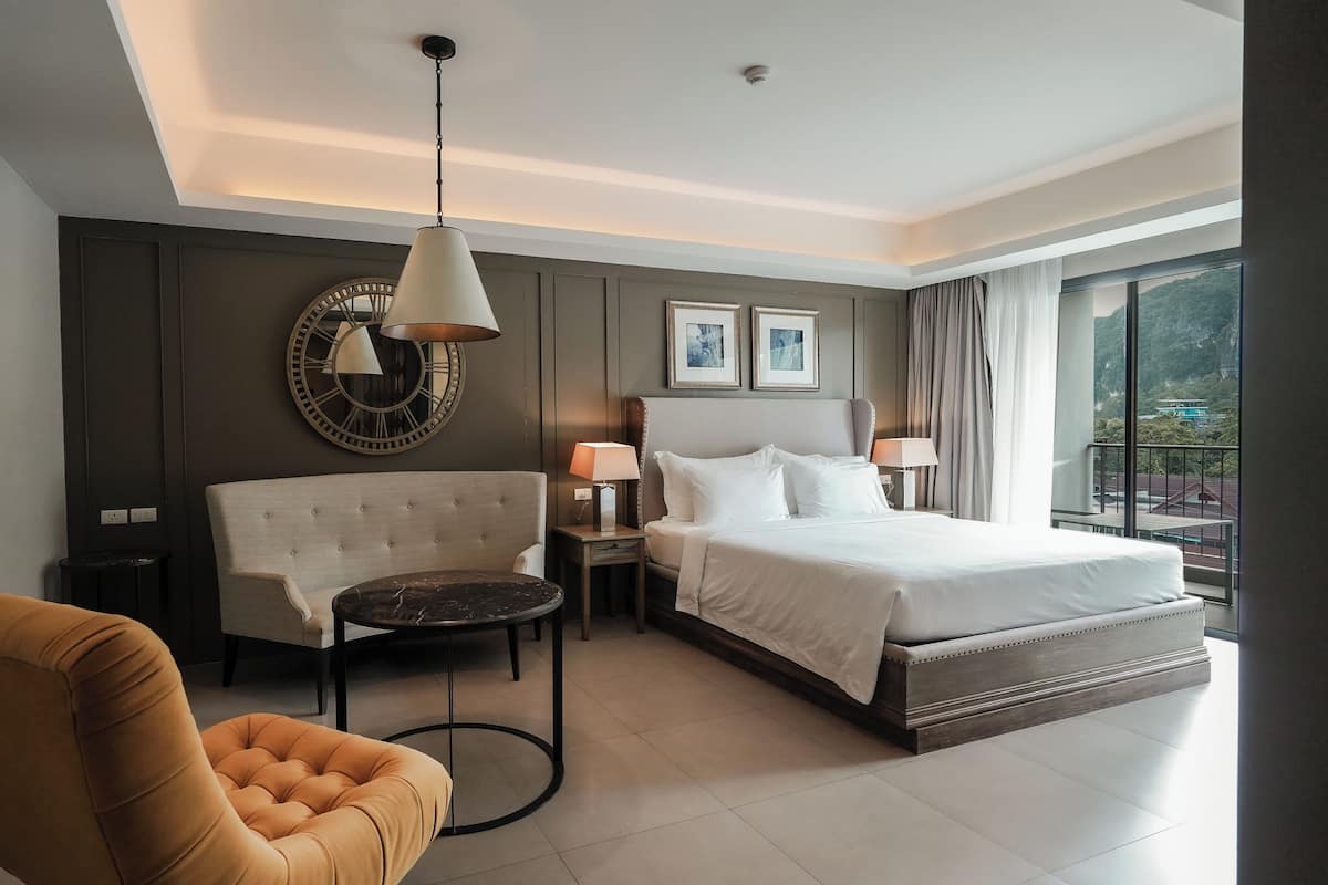 Habitación de hotel con cama, sofá, mesa y un amplio ventanal con vistas.