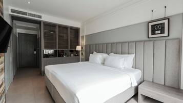 Ein modernes Hotelzimmer mit einem großen Bett, einem Nachttisch, einem Spiegel und einem gerahmten Bild an der Wand.