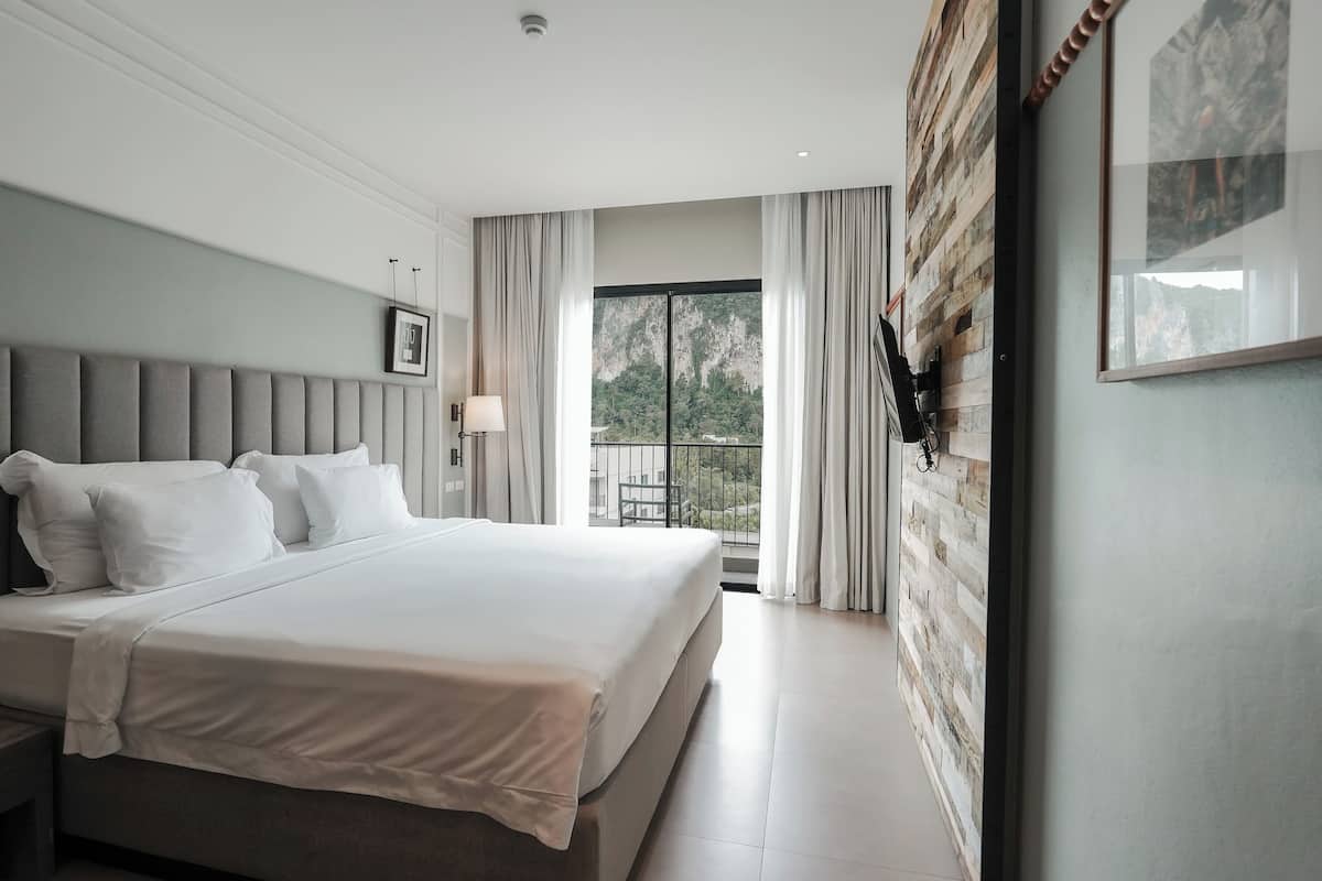 Una habitación de hotel moderna con una cama grande, vistas al exterior y una pared de acento de madera.