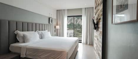 A modern hotel room with a large bed, a view of the outdoors, and a wooden accent wall.