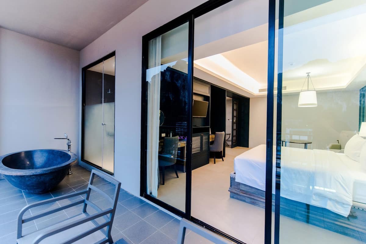 Una habitación de hotel moderna con una bañera grande, una cama y un escritorio.