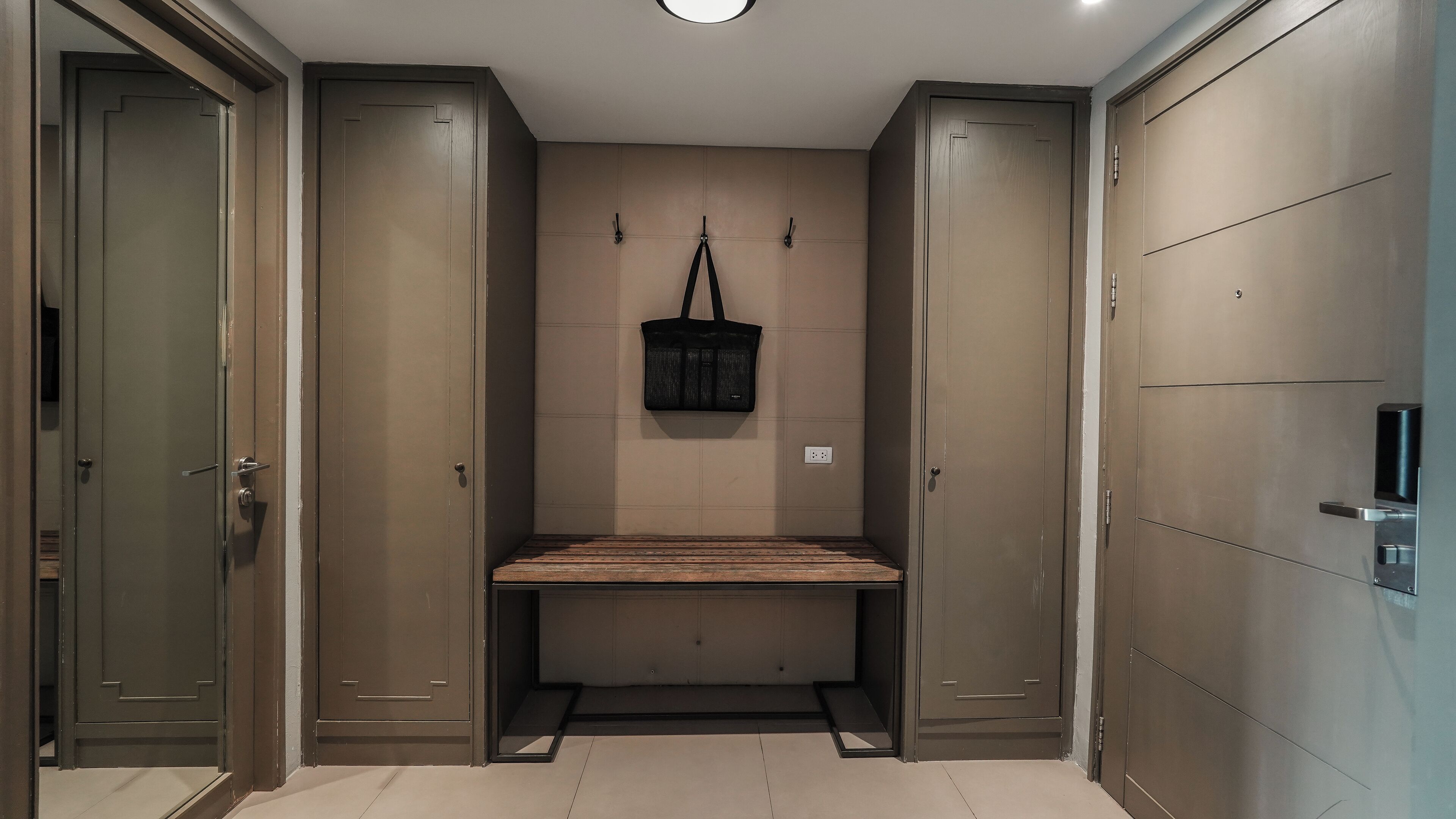 Un baño moderno y minimalista con un banco, perchero para toallas y una bolsa colgada.