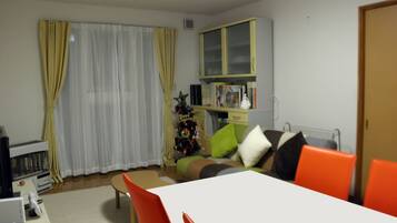 A living room with a white table, orange chairs, a Christmas tree, and a bookshelf.