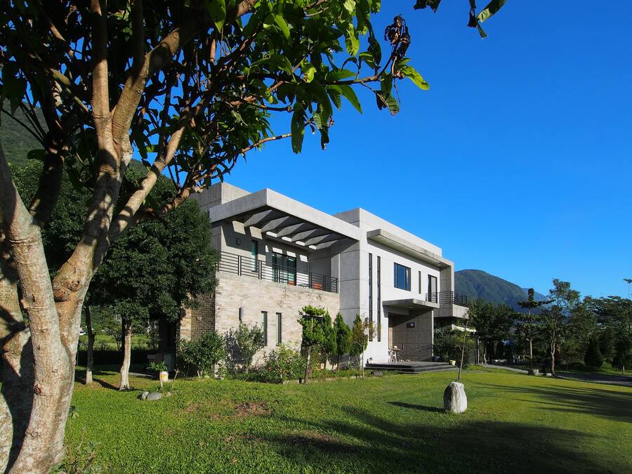 A modern two-story house with a stone facade, large windows, and a covered porch.