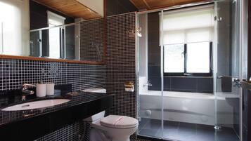 Uma casa de banho moderna com painel de azulejos preto e branco, cabine de duche em vidro e sanita branca.