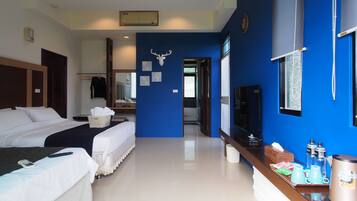 A hotel room with two beds, a TV, a minibar, and a bathroom visible through an open door.