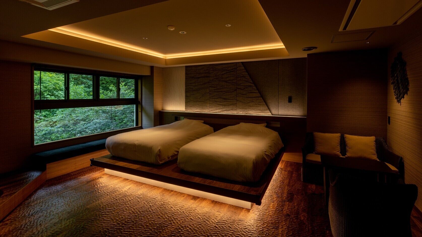 A modern bedroom with a large window, a bed, and a seating area.