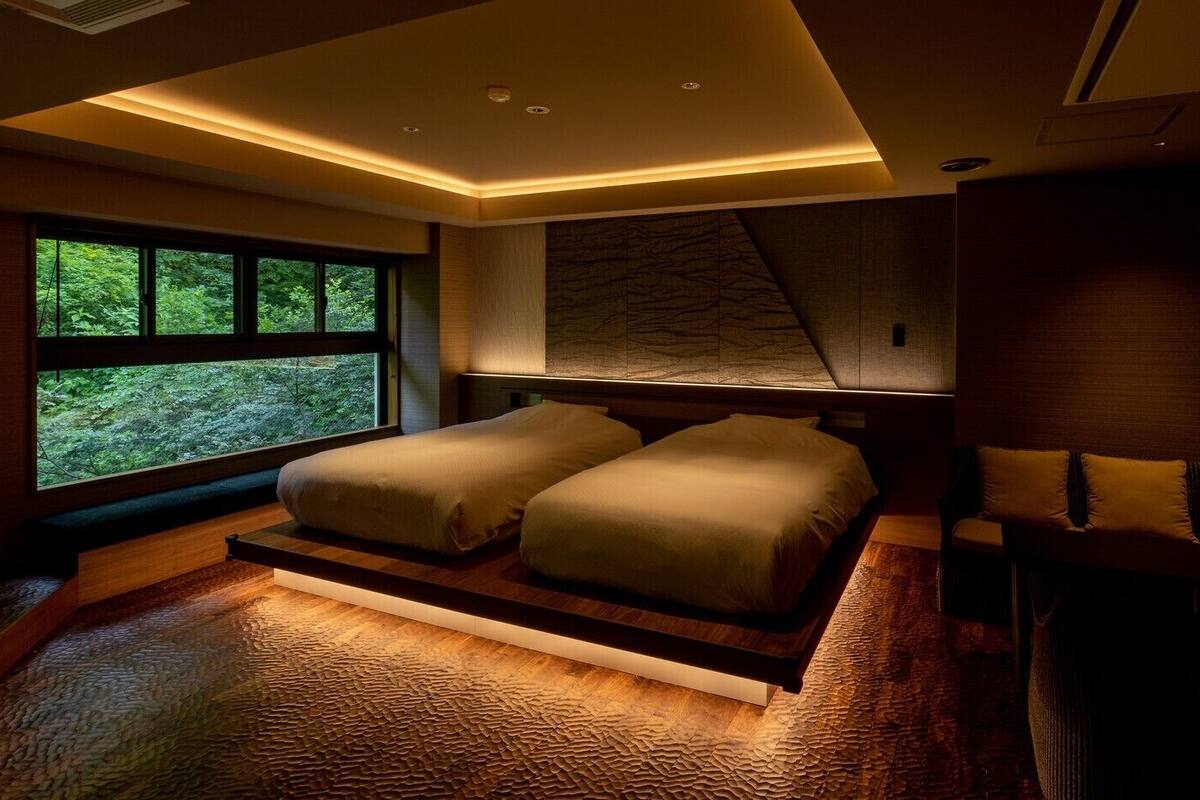 A modern bedroom with a large window, a bed, and a seating area.