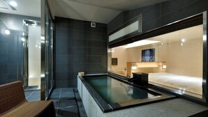 A modern spa room with a large soaking tub, a wooden bench, and a separate shower area. - Sake Hotel Tamakiya (Tokamachi)