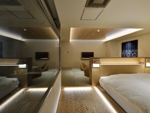 Quarto de hotel moderno com uma cama grande, área de estar e televisão.