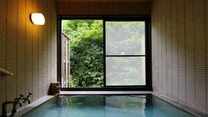 An indoor swimming pool with a view of lush greenery through a large window. - Sake Hotel Tamakiya (Tokamachi)