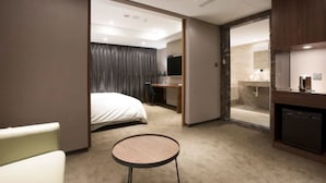 Et hotelværelse med seng, skrivebord, et lille bord, badeværelse med spejl og håndvask.